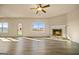 Spacious living room featuring a ceiling fan, fireplace, large windows, and wood flooring at 2381 Aukerman Trce # 81, Hampton, GA 30228