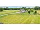 Aerial view of a barn-style home with a long drive and fenced pastures, surrounded by green fields at 290 Weldon Rd, Fayetteville, GA 30215