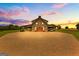 Stunning exterior view of barn with covered parking and large driveway with brick pavers at sunset at 290 Weldon Rd, Fayetteville, GA 30215