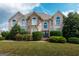 Elegant two-story home with a brick and stone facade, arched windows, and manicured landscaping at 313 Masters Club Blvd, Hampton, GA 30228