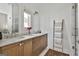 Elegant bathroom with double sinks, marble countertops, and a bright window, accented by wood cabinetry at 145 Kelmscott Ln, Fayetteville, GA 30214
