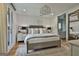 Bright main bedroom with a plush bed, designer chandelier, and access to an en suite bathroom at 145 Kelmscott Ln, Fayetteville, GA 30214