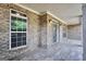 Charming covered porch with brick accents, decorative lighting, and wood-look tile flooring at 204 Carmell Ct, Mcdonough, GA 30252