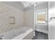 Bathroom tub and shower area with marble walls, slate tile floors, and a window for natural light at 203 Shelby Ln, Fayetteville, GA 30215