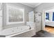 Bathroom featuring a standalone soaking tub, a glass shower, and natural light from a large window at 203 Shelby Ln, Fayetteville, GA 30215