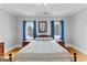 Sunlit bedroom featuring hardwood floors, two windows with blue curtains, and classic furnishings, creating a cozy retreat at 203 Shelby Ln, Fayetteville, GA 30215