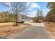 Exterior shot of large home with a circular driveway, multiple garages, and a well-maintained front lawn and surrounding trees at 203 Shelby Ln, Fayetteville, GA 30215