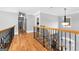 Upstairs hallway featuring hardwood floors, wood and iron railing, and decorative lighting at 203 Shelby Ln, Fayetteville, GA 30215