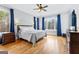 Bright main bedroom with hardwood floors, ceiling fan, and large windows with blue curtains at 203 Shelby Ln, Fayetteville, GA 30215