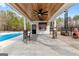 Elegant pool house with a cedar plank ceiling, fan, lights, bar, and stone pillars offering a stylish outdoor entertainment space at 203 Shelby Ln, Fayetteville, GA 30215