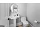 Powder room with pedestal sink, round mirror, and tiled floors at 203 Shelby Ln, Fayetteville, GA 30215