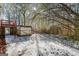 Snowy backyard featuring a weathered shed, dense trees and an extension of a wooden deck at 5552 Smithfield Rd, Bowdon, GA 30108