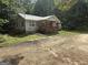 View of charming home with metal roof, covered front porch and surrounded by trees at 5552 Smithfield Rd, Bowdon, GA 30108
