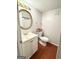 Cozy powder room with white vanity, a round mirror, and hardwood flooring at 1448 Pine Log Ne Rd # C, Conyers, GA 30012