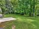 Lush backyard featuring a well-maintained lawn, mature trees, and a patio area for outdoor entertaining at 45 Plantation Ln, Locust Grove, GA 30248