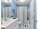 Bright blue bathroom featuring a shower with a striped curtain, a vanity with sink, and blue towels at 495 Stonehaven Dr, Fayetteville, GA 30215