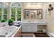 A bright bathroom featuring a jacuzzi tub, white vanity and large mirror at 495 Stonehaven Dr, Fayetteville, GA 30215
