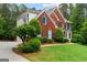 Well-maintained brick home featuring mature trees, lush lawn, and a charming façade with complementary architectural details at 495 Stonehaven Dr, Fayetteville, GA 30215