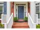 Inviting front entrance with a classic blue door, brick steps, and white railings enhanced by elegant outdoor lighting at 495 Stonehaven Dr, Fayetteville, GA 30215