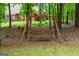 Relaxing wooden swing beneath mature trees, providing a peaceful retreat in a natural setting at 495 Stonehaven Dr, Fayetteville, GA 30215