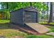 Metal storage building with ramp, perfect for tools, equipment, or vehicle storage, set in a wooded backyard at 1147 Tanglewood Rd, Jonesboro, GA 30236
