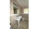 Well-lit bathroom with tiled floor, pedestal sink, toilet, and decorative mirror at 9163 Fair Sw St, Covington, GA 30014