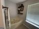Bright bathroom featuring a soaking tub with shelves for storage and a window with blinds at 800 Attaway Rd, Bowdon, GA 30108