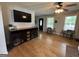 Open-concept living room featuring a TV, wooden floors, dog kennel, and neutral-toned furnishings at 800 Attaway Rd, Bowdon, GA 30108