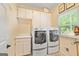 Convenient laundry room featuring side-by-side washer and dryer, ample storage, and bright window at 255 Emerald Lake Dr, Fayetteville, GA 30215