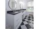 Bathroom featuring dual sinks, black countertops, white cabinets, a window, and a checkerboard floor at 211 Hogan Coweta Rd, Hogansville, GA 30230