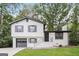 Charming two-story home with a well-manicured lawn, painted white brick and siding, and a grey garage door at 1590 Sw Cherry Hill Ln, Conyers, GA 30094