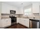 Updated kitchen featuring stainless steel appliances, white cabinets, granite counters, and hardwood floors at 1590 Sw Cherry Hill Ln, Conyers, GA 30094