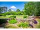 Beautiful landscaping featuring a stone retaining wall and lush greenery beneath a clear blue sky at 1745 Stripling Chapel Rd, Carrollton, GA 30116