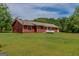 Expansive backyard features a well-maintained lawn and a charming red home exterior, perfect for outdoor activities at 1170 Peeksville Rd, Locust Grove, GA 30248