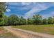 Gravel driveway leading to a red home surrounded by mature trees and a lush green lawn at 1170 Peeksville Rd, Locust Grove, GA 30248