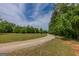 Curving gravel driveway surrounded by trees leading to a property under a partly cloudy sky at 1170 Peeksville Rd, Locust Grove, GA 30248
