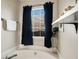 Inviting bathroom features a deep soaking tub with dark curtains, a window, and a display shelf at 351 Autumn Lake Dr, Mcdonough, GA 30253