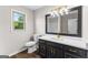 Elegant bathroom featuring dark vanity, gold hardware, quartz counters, and a window with outside view at 550 Davis Rd, Fayetteville, GA 30215