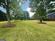 A view of a large grassy backyard with scattered trees, and the home's exterior on the right at 1040 Rock Creek Rd, Social Circle, GA 30025