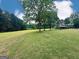 A large, grassy backyard with scattered trees and an outbuilding in the distance at 1040 Rock Creek Rd, Social Circle, GA 30025