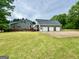 Backyard view featuring a spacious lawn, attached garage, and exterior staircase to a second-story porch at 1040 Rock Creek Rd, Social Circle, GA 30025