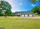 The rear exterior of the home features an attached three-car garage and a well-manicured lawn at 1040 Rock Creek Rd, Social Circle, GA 30025