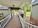 View of the wood porch with white railing, brick foundation and green lawn at 1040 Rock Creek Rd, Social Circle, GA 30025