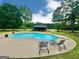An in-ground pool with lounge chairs, lush landscaping, and an outbuilding at 1040 Rock Creek Rd, Social Circle, GA 30025
