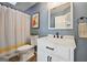 Charming bathroom with blue walls features a white vanity and tub with a patterned shower curtain at 612 Longer Dr, Peachtree City, GA 30269