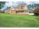 This two-story home boasts a brick facade, covered porch, and lush green lawn extending to mature trees at 612 Longer Dr, Peachtree City, GA 30269