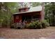 Exterior view of a cozy cabin-style home surrounded by lush greenery and mature trees at 695 Frog Rd, Locust Grove, GA 30248