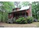 Exterior view of a charming cabin-style home with a covered porch and landscaped yard at 695 Frog Rd, Locust Grove, GA 30248