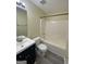 A simple bathroom with a dark vanity, sink, toilet, and a shower-tub combination with a white surround at 253 Whistle Way, Locust Grove, GA 30248