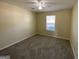 A clean and bright bedroom featuring neutral walls, carpet, and a window for natural light at 253 Whistle Way, Locust Grove, GA 30248